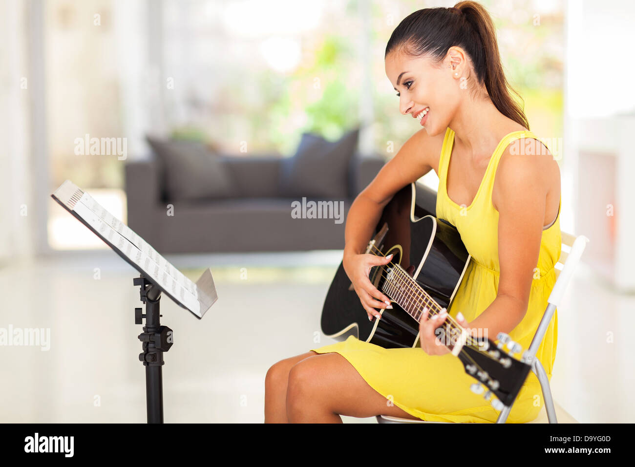 smiling pretty young woman playing guitar at home Stock Photo - Alamy