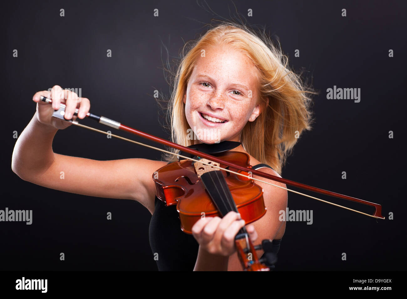 cheerful preteen girl playing violin on black background Stock Photo