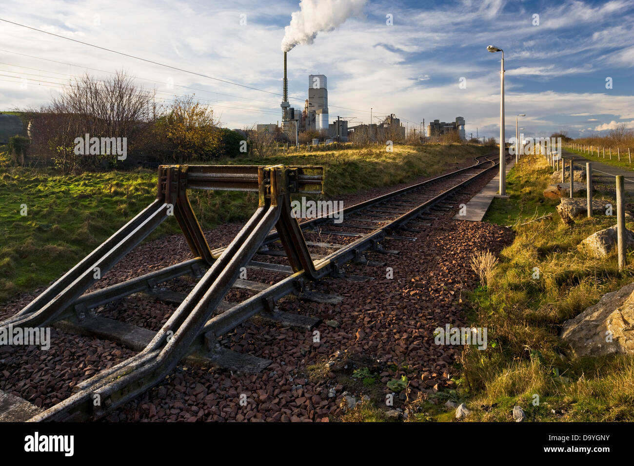 Deserted railroad track with a cement factory in the background, Dunbar, East Lothian, Scotland Stock Photo
