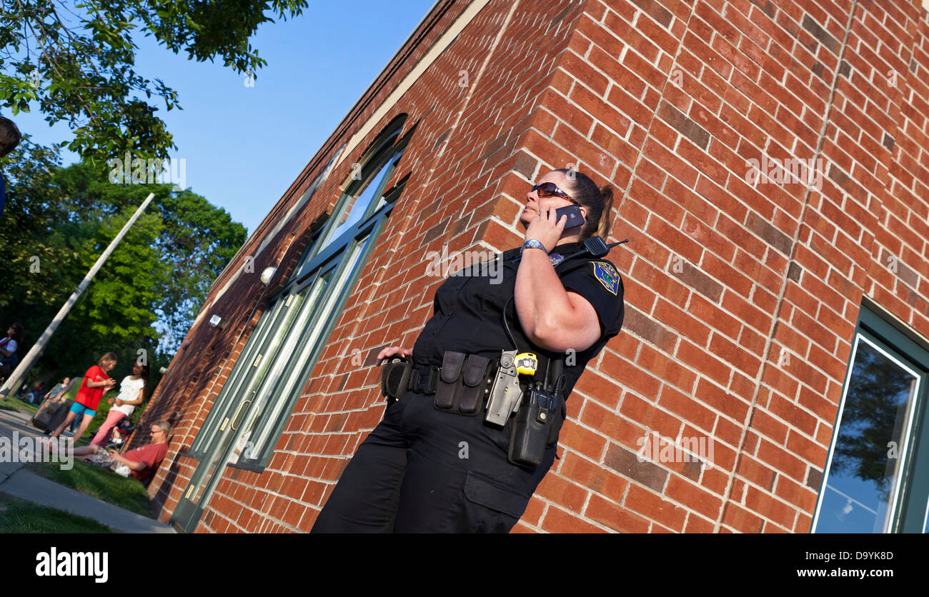 A police officer talks on her phone while providing security during an event. Stock Photo