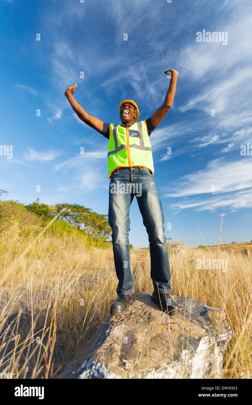 successful African construction worker with arms outstretched outdoors Stock Photo