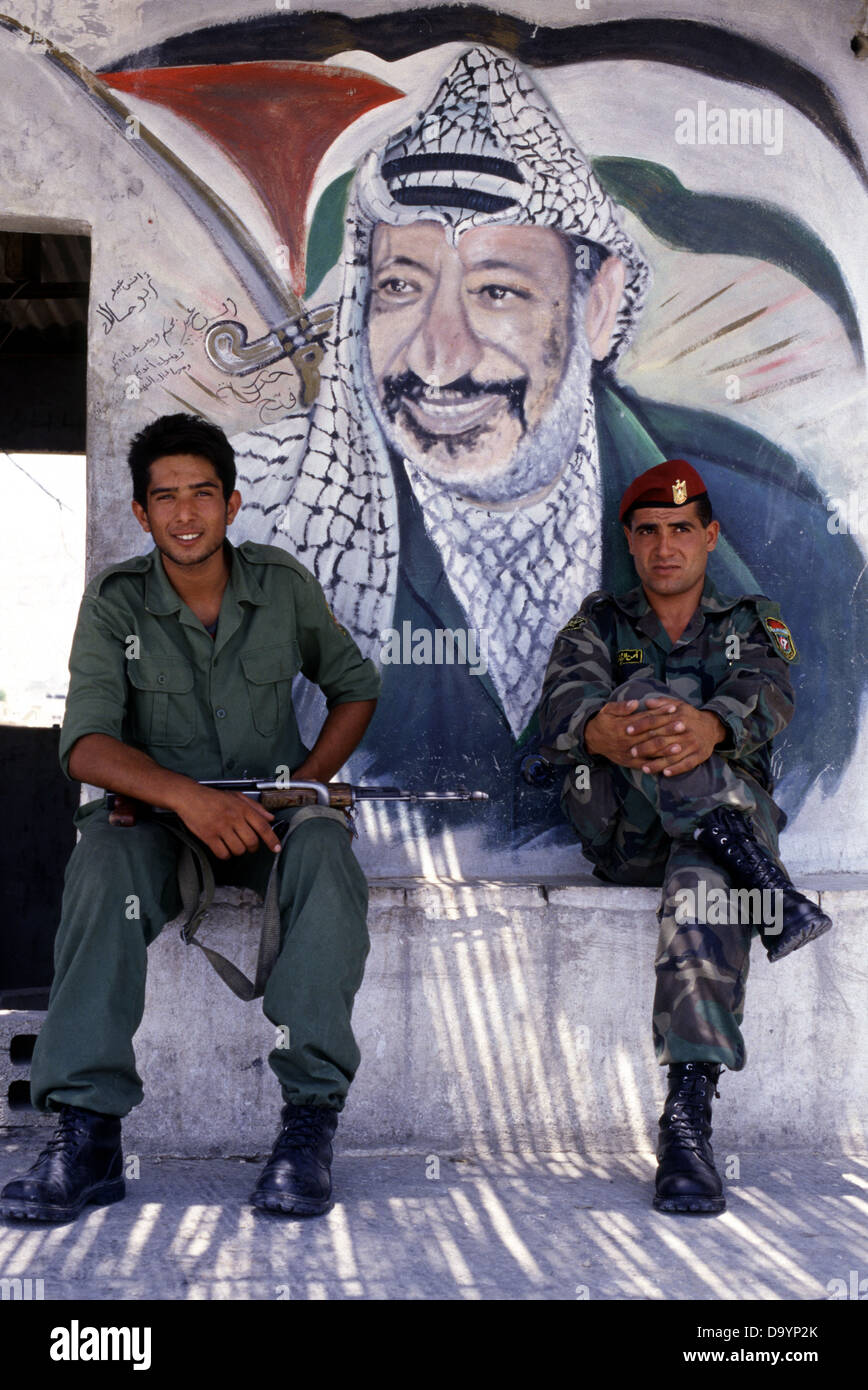 Members of the Palestinian Security Services sit in front of a painted figure of Yasser Arafat who was a Palestinian political leader and Chairman of the PLO Palestine Liberation Organization in the city of Jericho West Bank Palestinian Authority territories Stock Photo