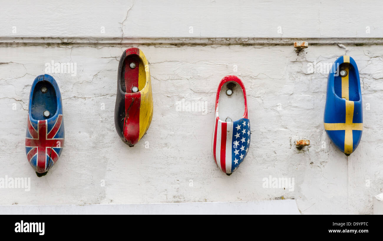 Wood clogs on a wall, painted in the national flag colors of four countries. Stock Photo