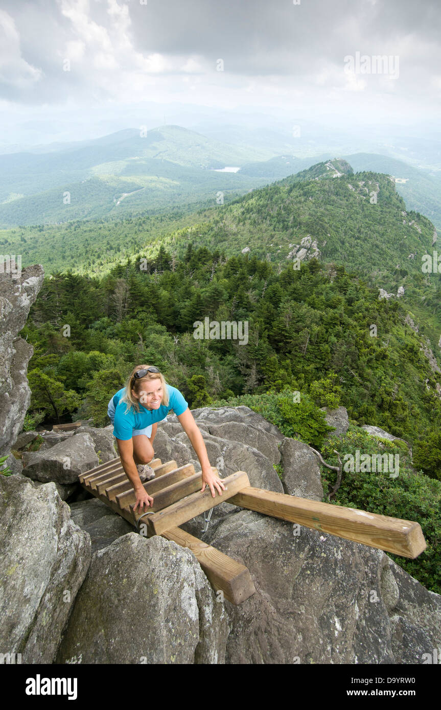 A woman climbing up a ladder in  Grandfather Mountain State Park, Linville, North Carolina. Stock Photo