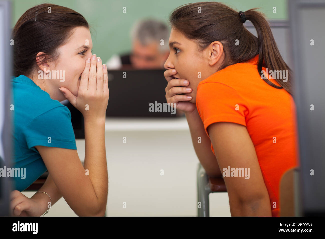 cute high school students gossiping in classroom Stock Photo