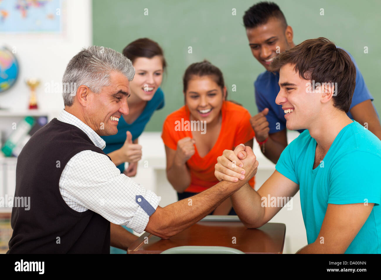 friendly middle aged teacher arm wrestling with high school student in
