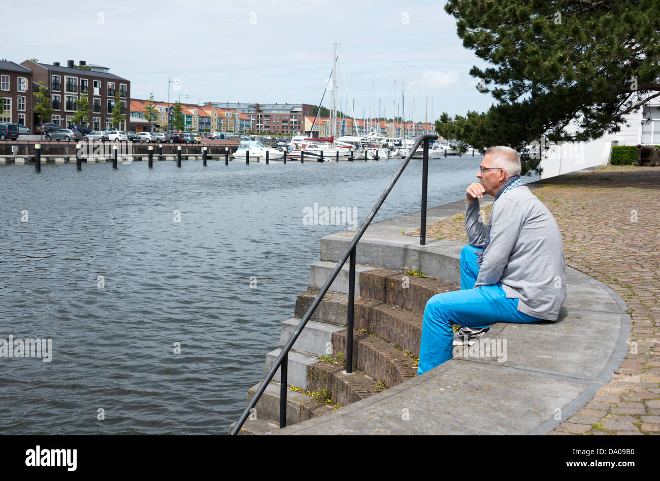 man sitting on the strairs to the water and thinking Stock Photo