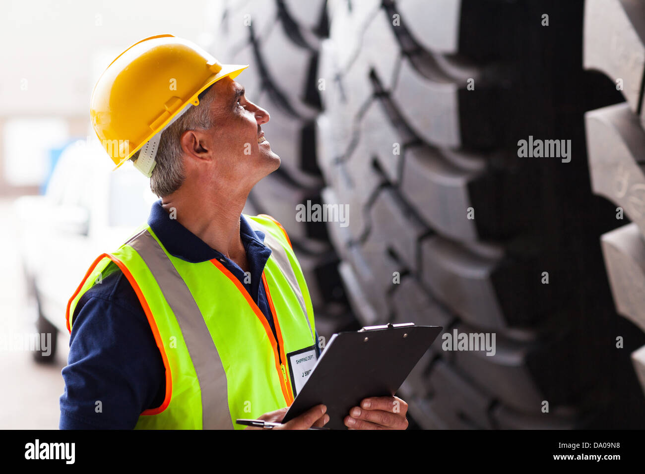 warehouse middle aged worker inspecting industrial tires before exporting Stock Photo