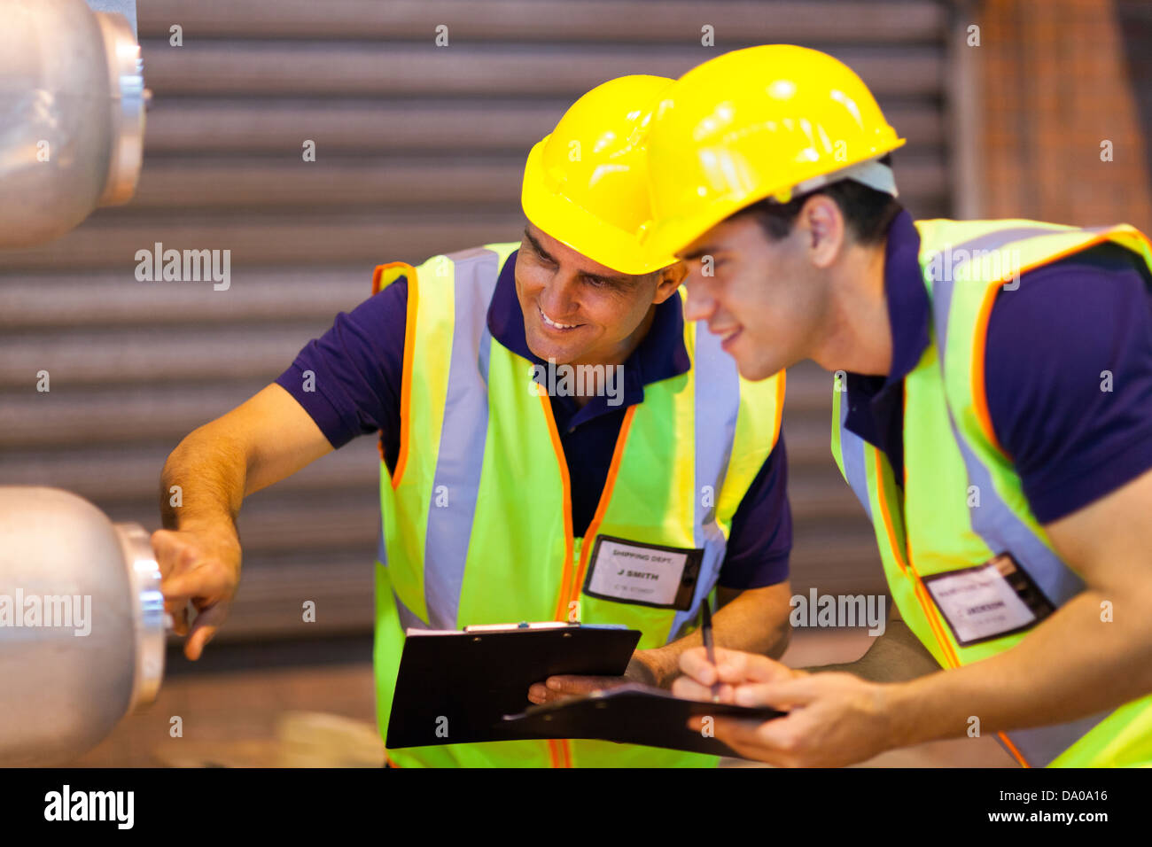 warehouse coworkers in safety gear inspecting machinery Stock Photo