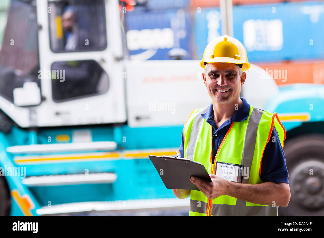 happy middle aged shipping worker standing big forklift Stock Photo