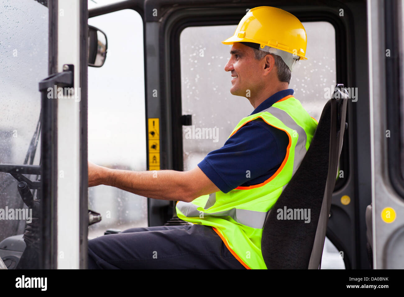 middle aged professional warehouse worker operating forklift Stock Photo