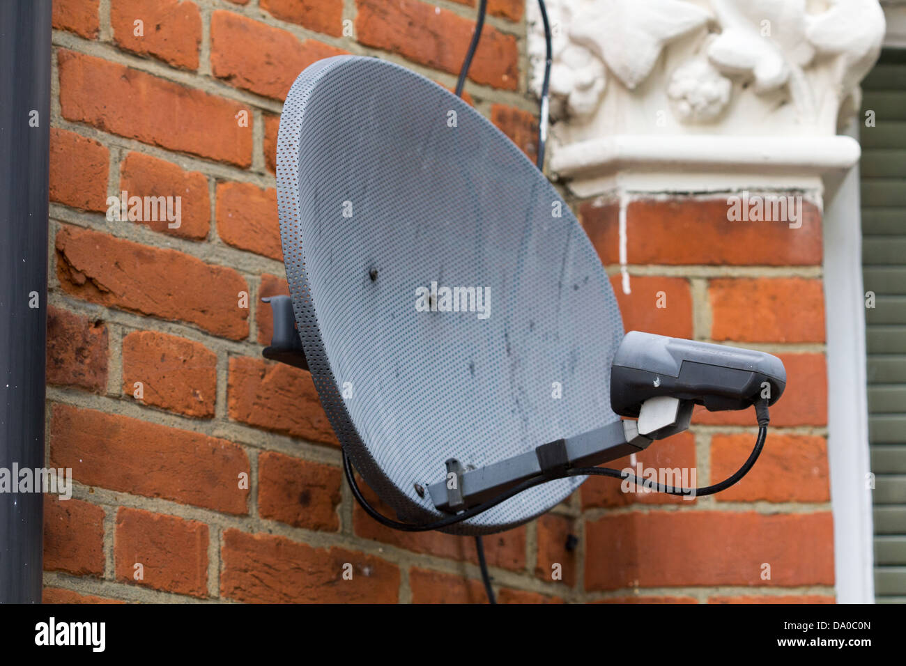 Weathered satellite dish on the side of a building Stock Photo