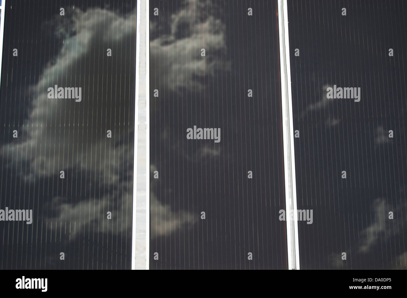 Solar panels reflecting a sunny blue and white cloud sky. Stock Photo