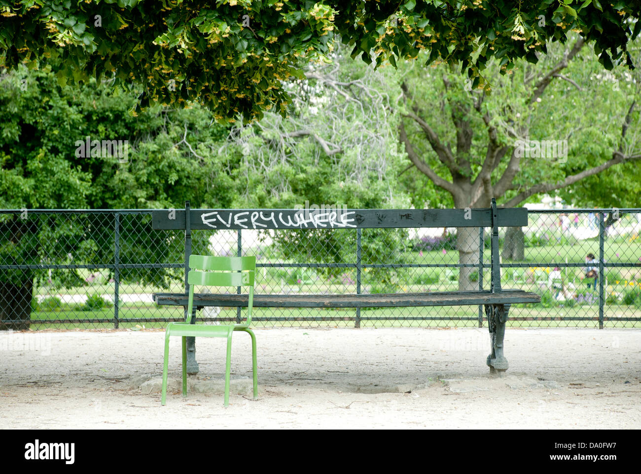 A wooden bench in Paris with the graffiti 'Everywhere' written on it in white paint. Stock Photo