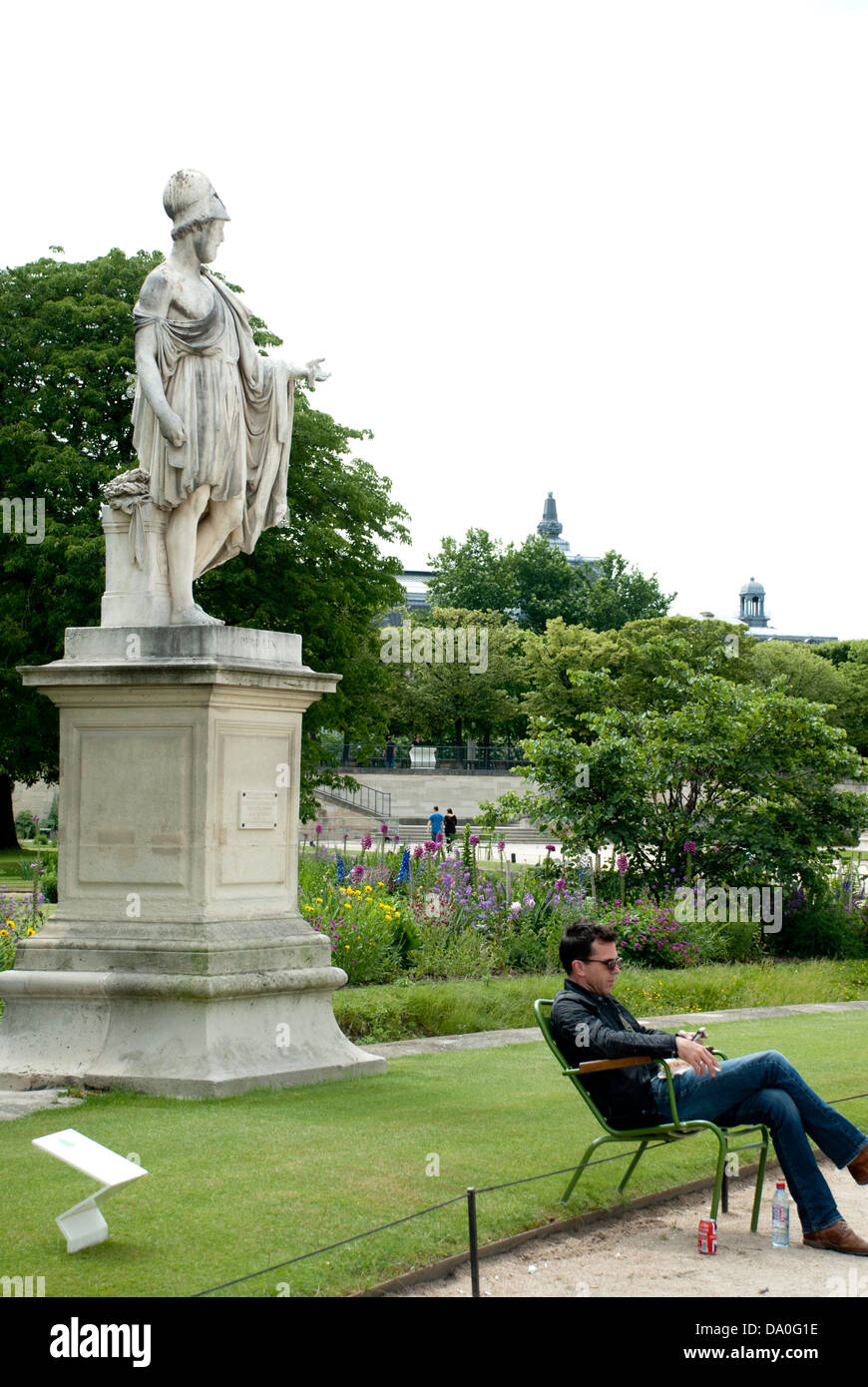 A man relaxing in a chair in the Jardin des Tuileries, Paris, next to a statue of Pericles, democratic emperor of old Athens. Stock Photo