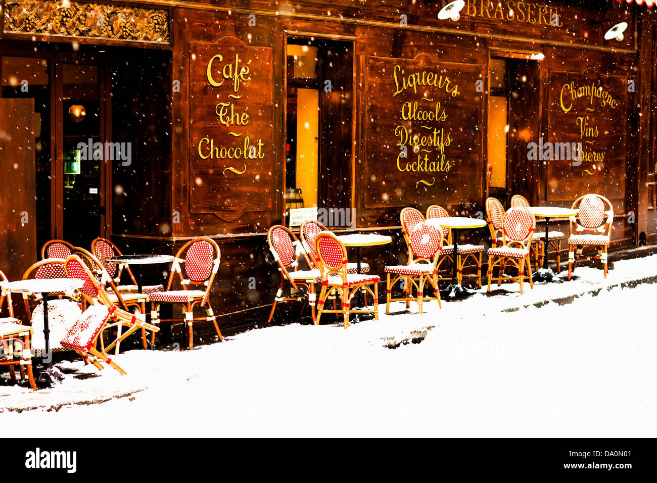 Wooden parisian coffee house with it's sidewalk tables and chairs in winter with the snow falling Stock Photo