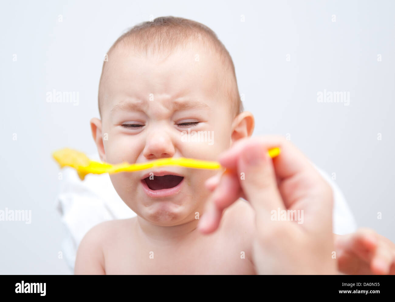 Angry baby doesn't like his meal. Simple background Stock Photo Alamy
