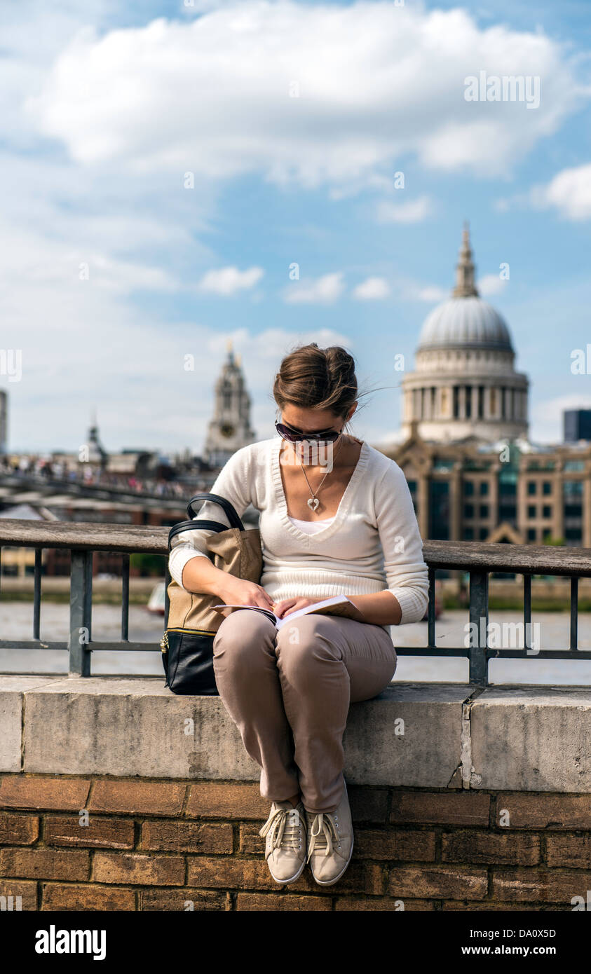 Young girl reading a book with St Paul Cathedral in the background South Bank London England Great Britain UK Europe Stock Photo