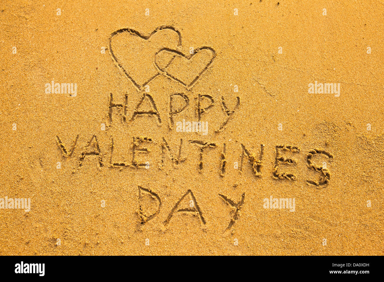 In the beach sand: Happy Valentine's Day and two hearts Stock Photo - Alamy