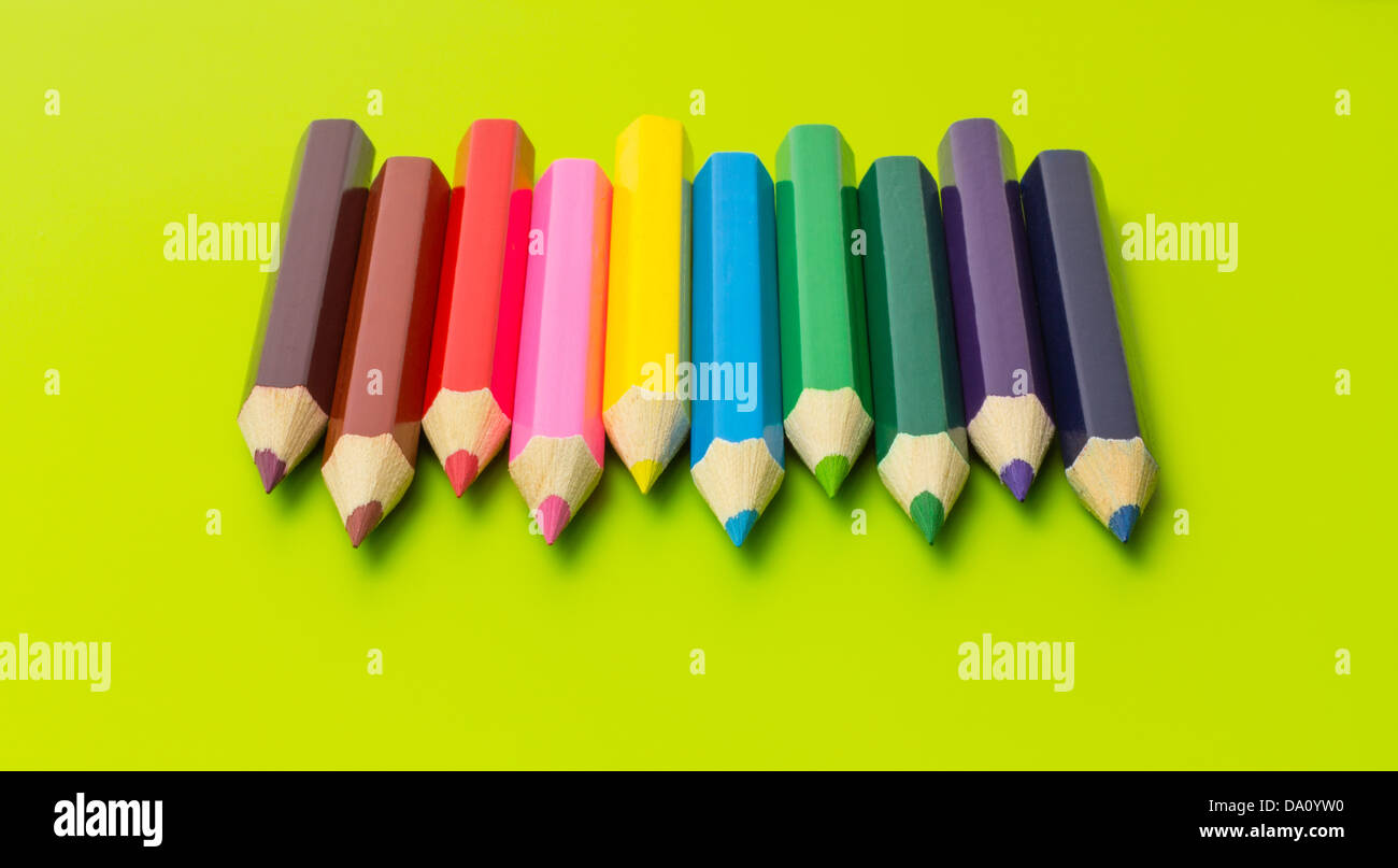 Set of colored pencils arranged in rainbow colors on olive green background Stock Photo