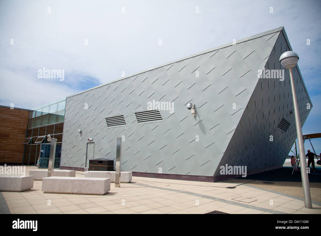 The Porth Eirias Centre, Colwyn Bay showing two storey glass & metal clad section of the building, outside showers & benches Stock Photo