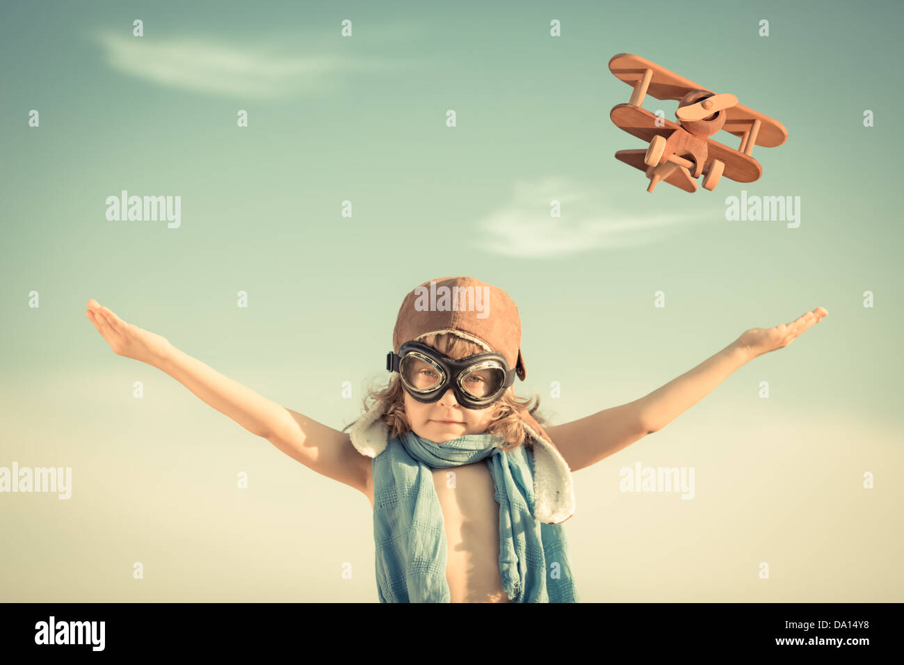 Happy kid playing with toy airplane against blue summer sky background ...