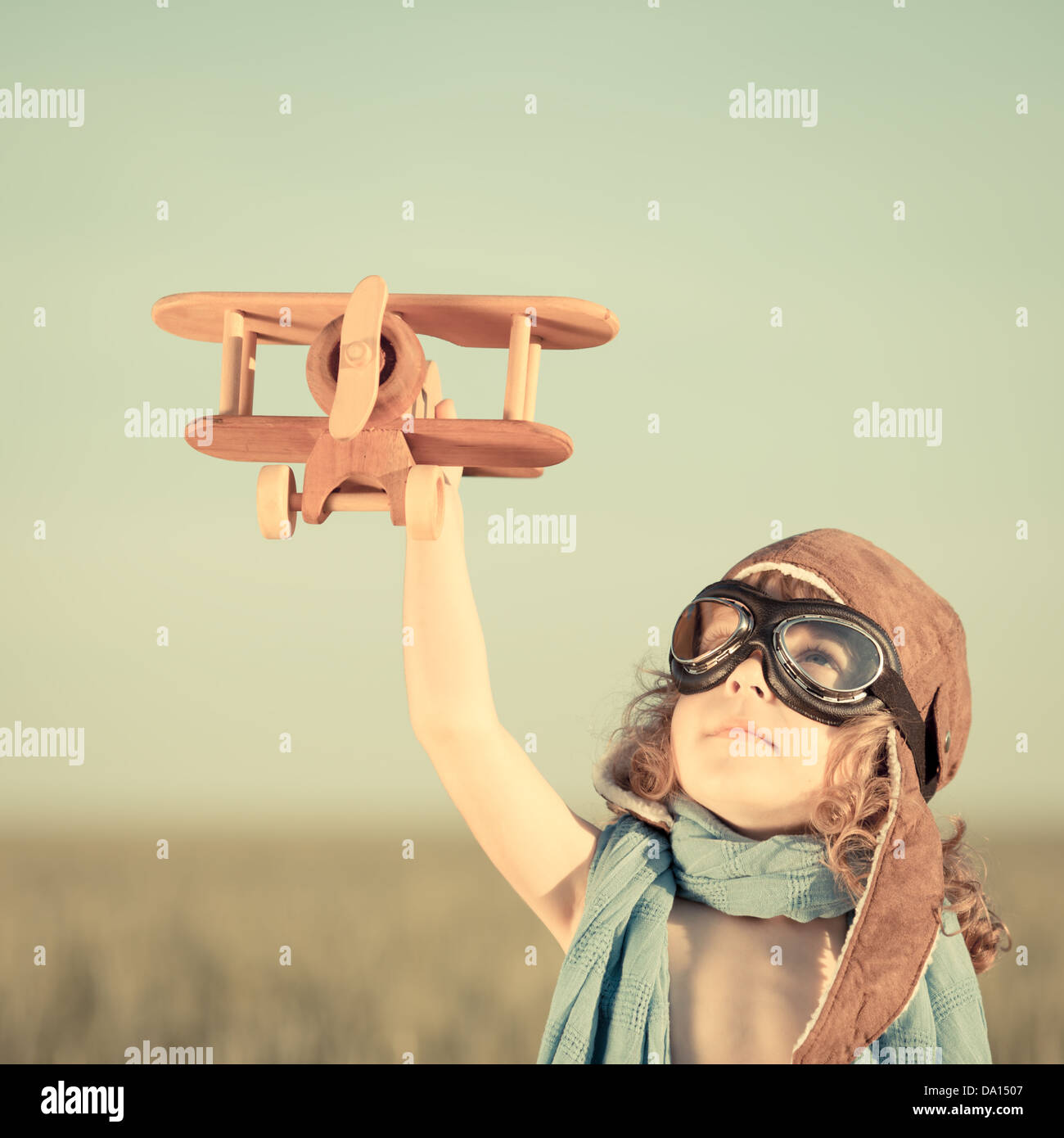Happy kid playing with toy airplane against blue summer sky background. Stock Photo