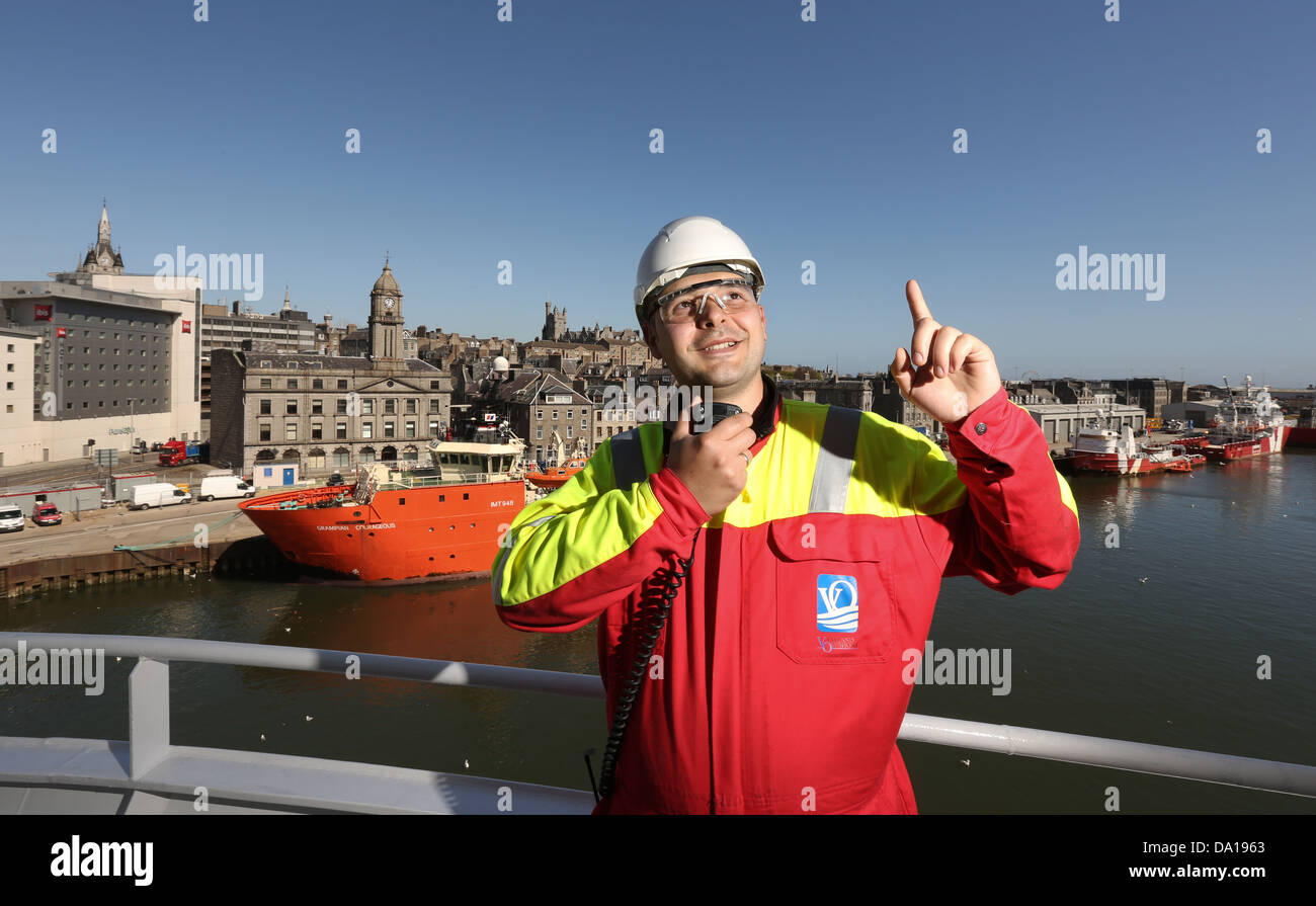 Worker signalling to crane operator while loading vessel at Aberdeen Harbour in the city centre, Scotland, UK Stock Photo