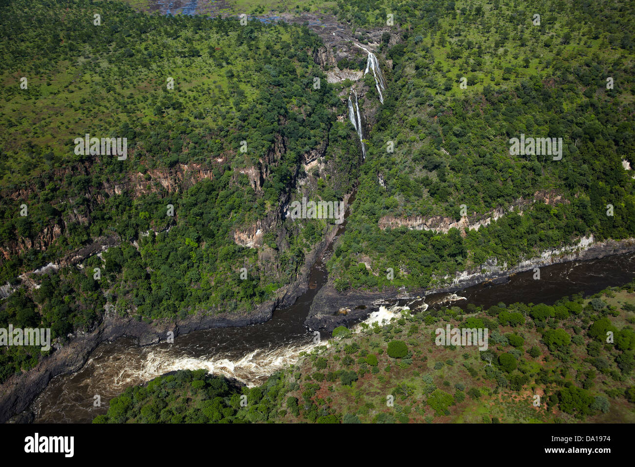 Waterfall flowing into Zambezi River in Batoka Gorge below Victoria Falls, Zimbabwe / Zambia Border, Southern Africa - aerial Stock Photo