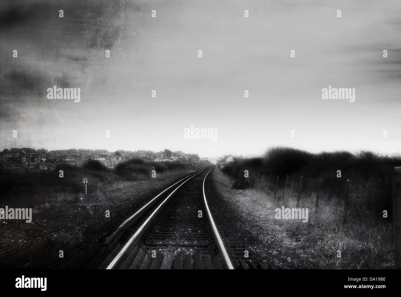 Single Rail Track Fading Into The Distance. Black and White, with a digitally enhanced texture and glow. Stock Photo