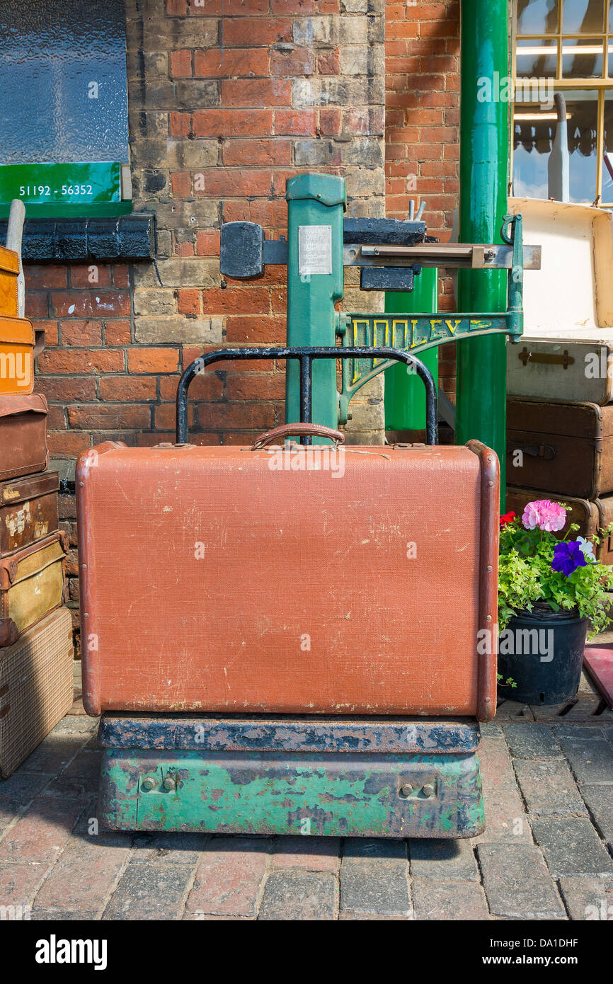Vintage suitcase bsing weighed on old fashioned railway scales. Stock Photo
