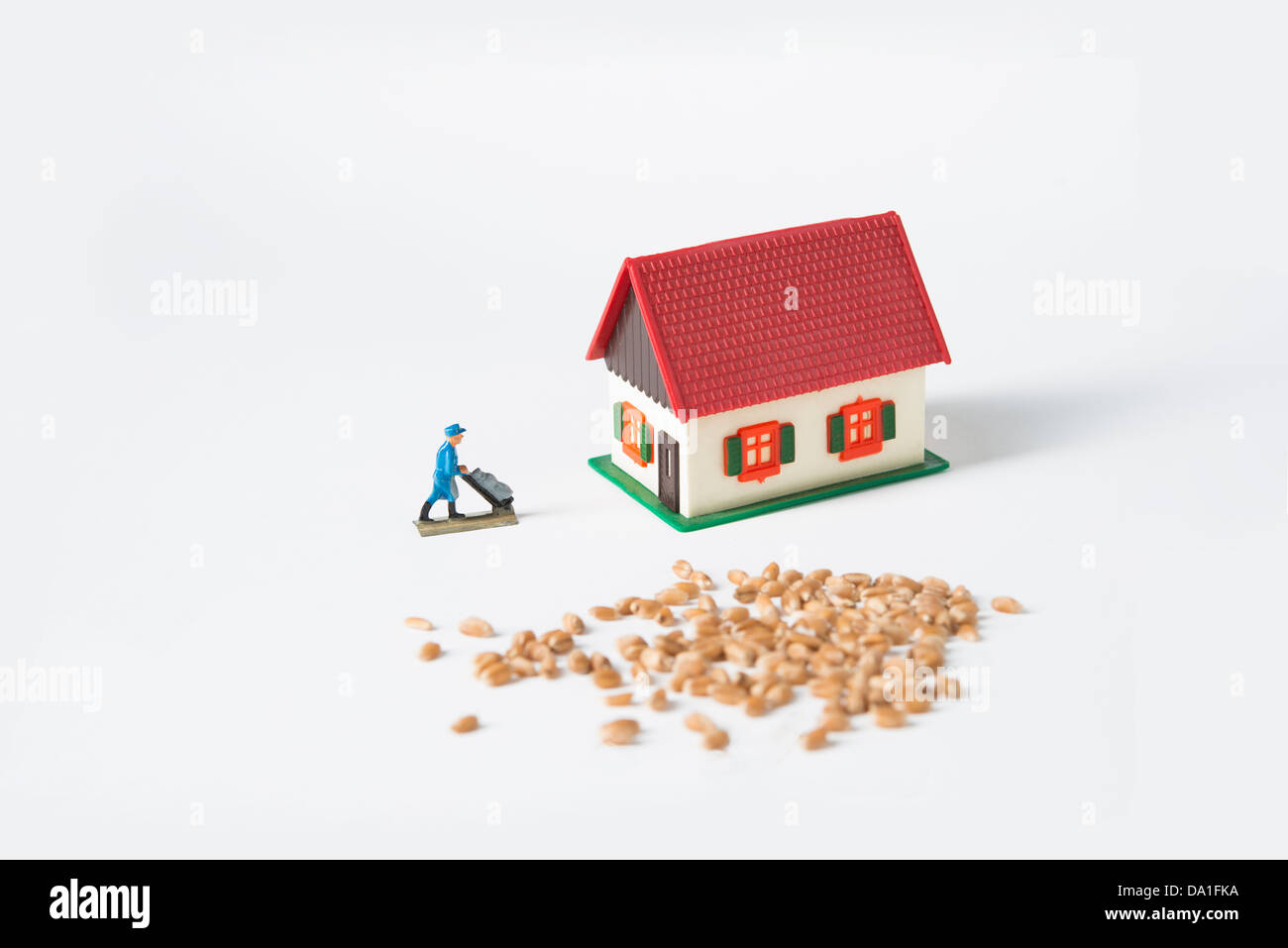 Scale model home with wheat seeds  and miniature worker carries bags of seeds Stock Photo