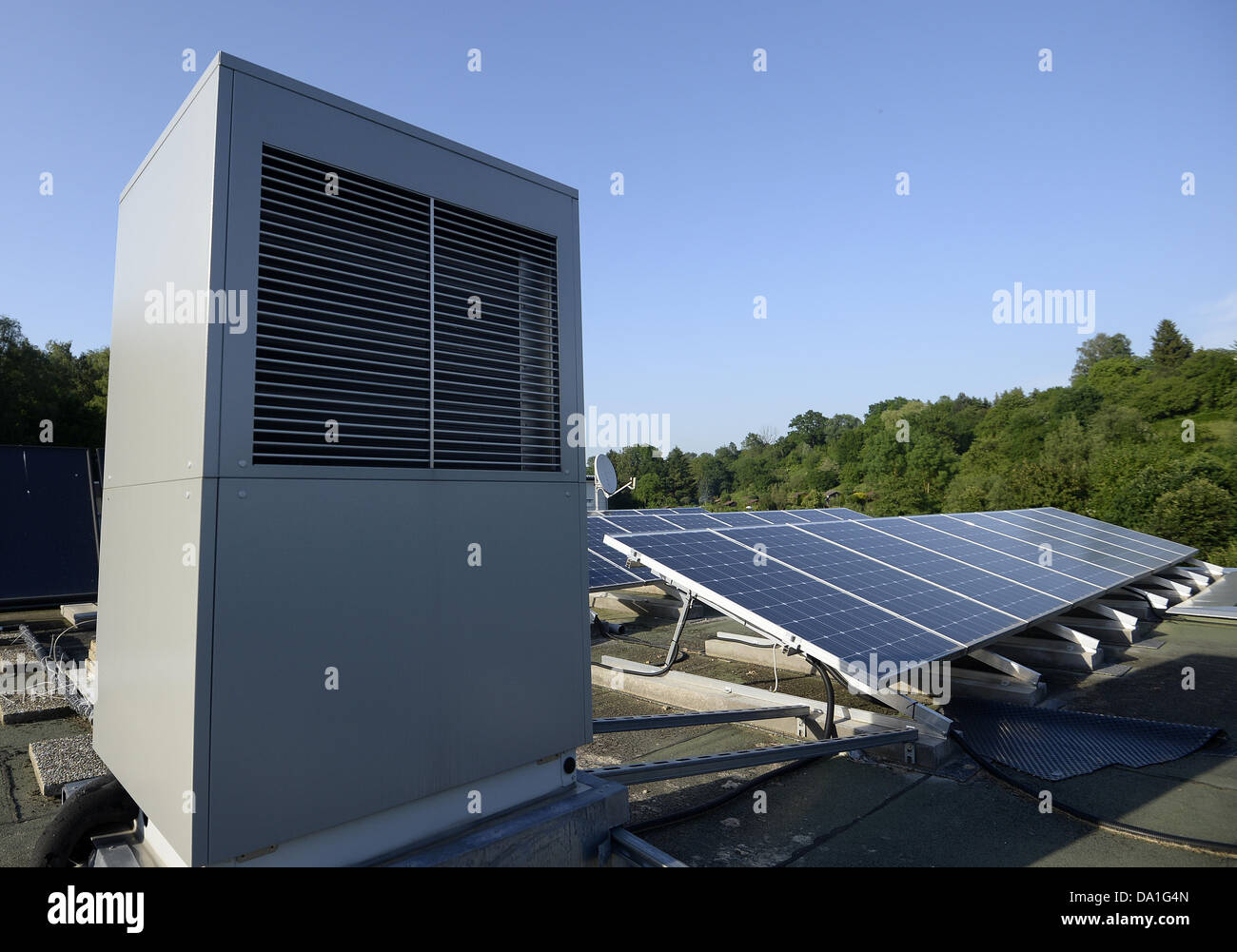 A heating pump and solar collectors are pictured on the roof of a ...