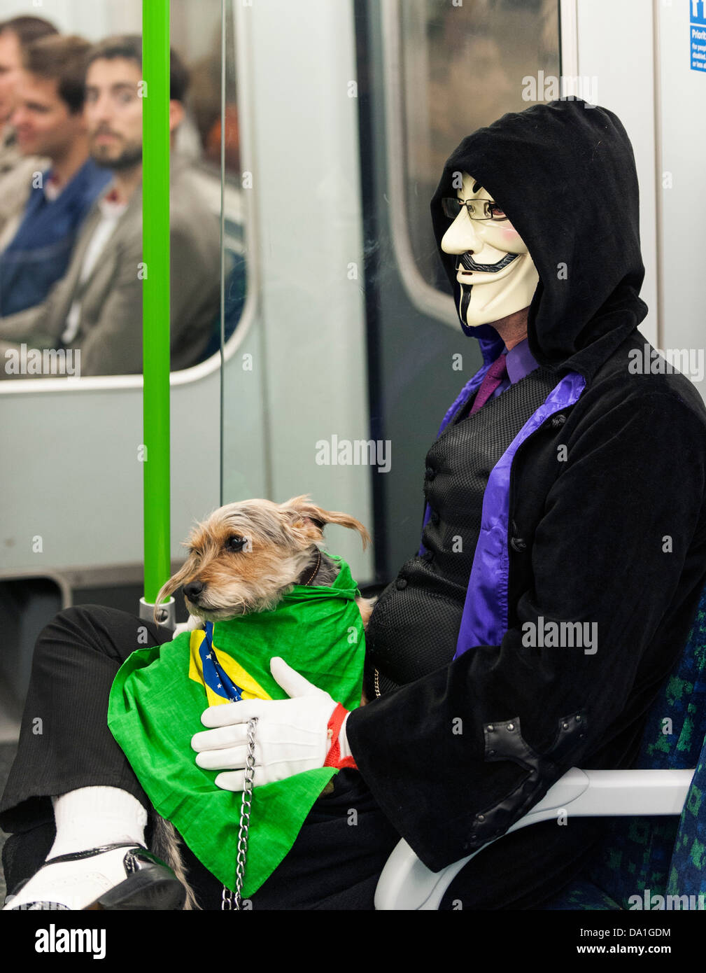 A tube passenger wearing a mask and holding a small dog on the London Underground tube train. Stock Photo