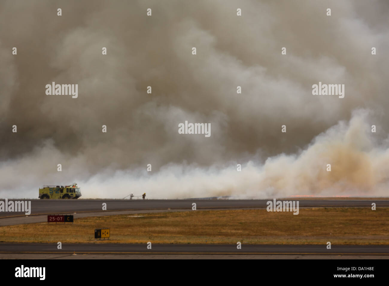 Firemen work to control brush fire as it burns fiercely sending flames and smoke high into the clouds Stock Photo