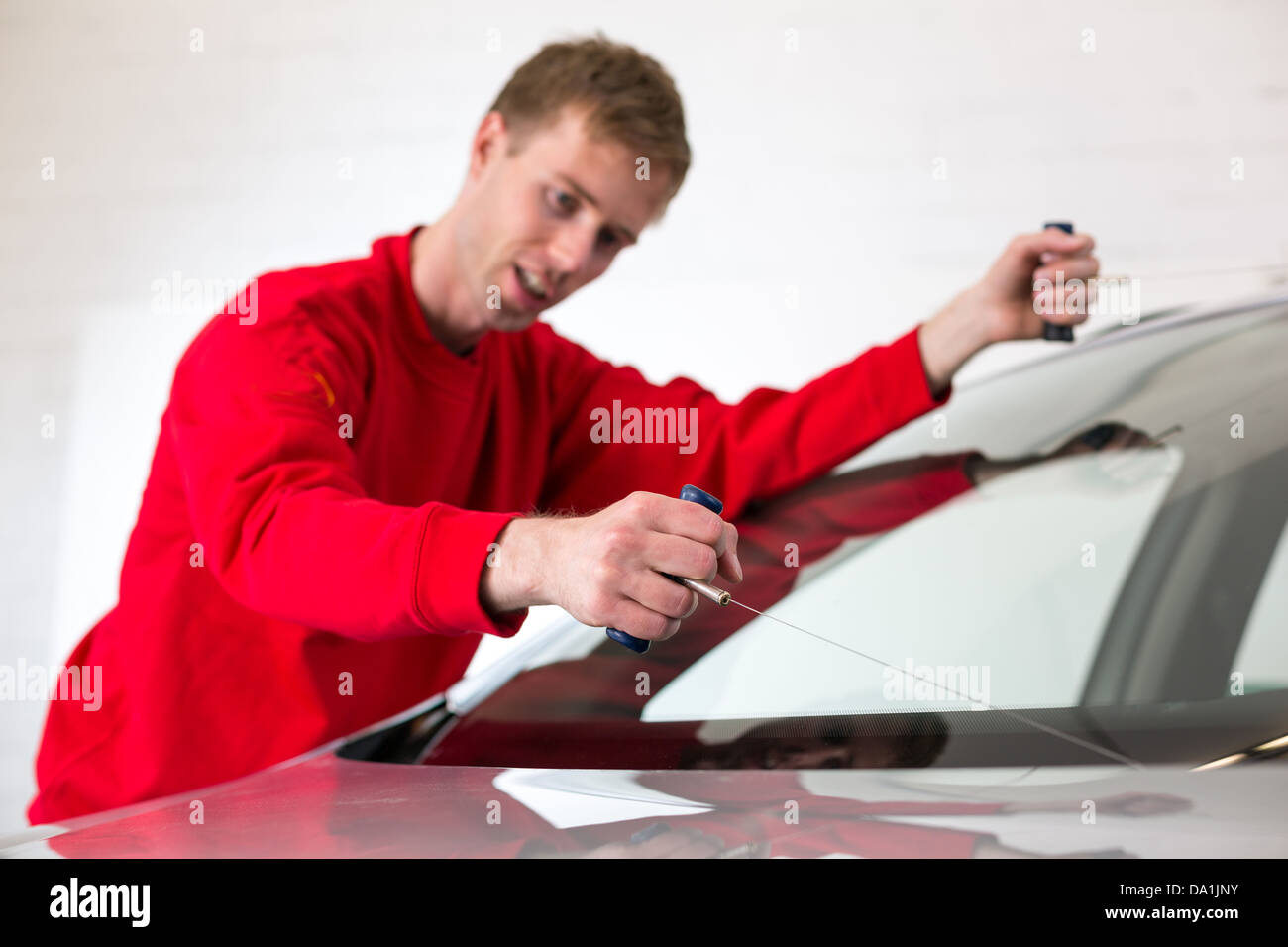 Glazier cutting adhesive of windscreen with a wire to replace windshield Stock Photo Alamy