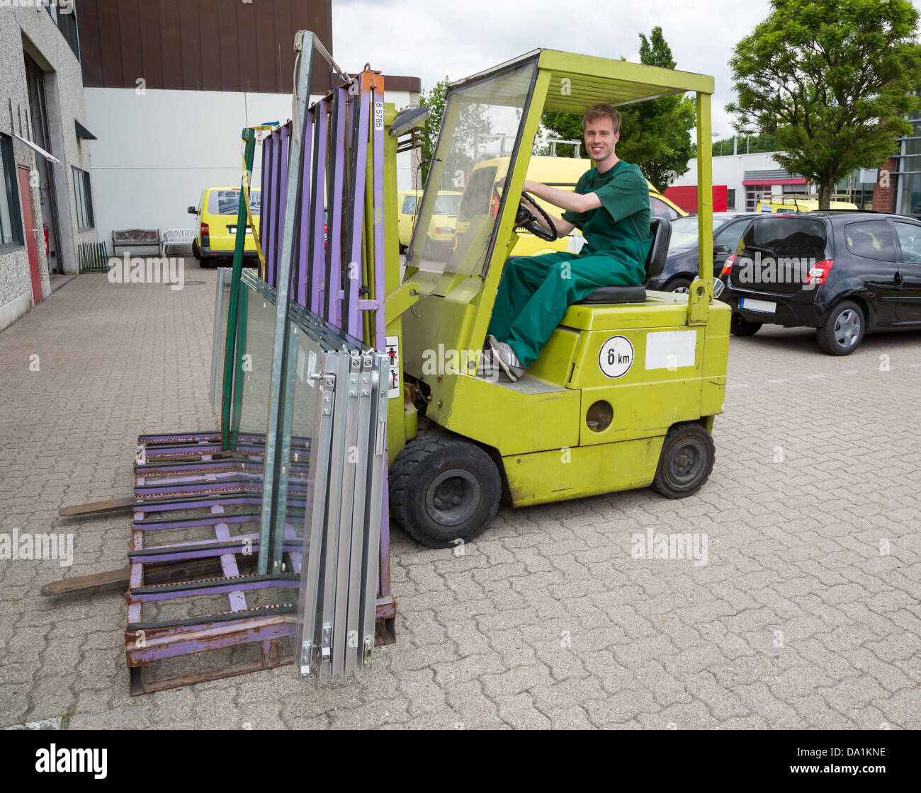 Glazier operating a forklift truck loaded with panes of glass Stock Photo