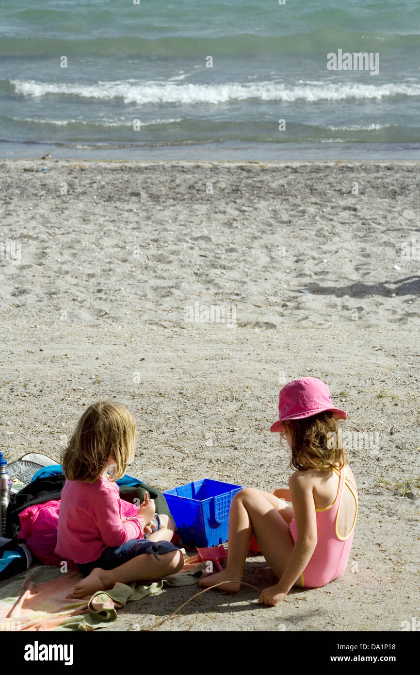Two little girls in pink enjoy the shore of Lake Taupo, Taupo, New Zealand. Stock Photo