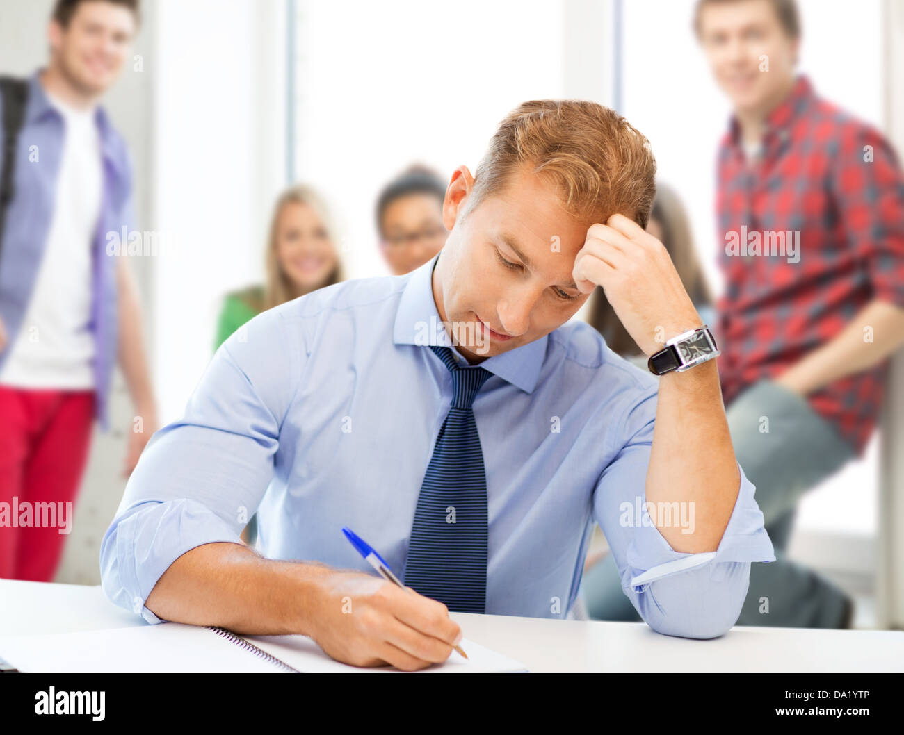 handsome teacher writing in notebook Stock Photo