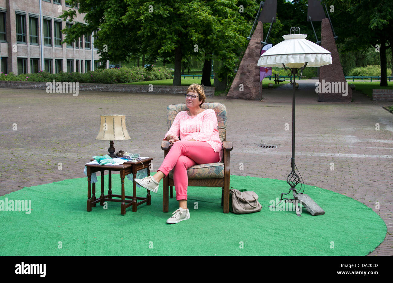 Adult woman thinking and sitting on chair in a park with table and lamp Stock Photo