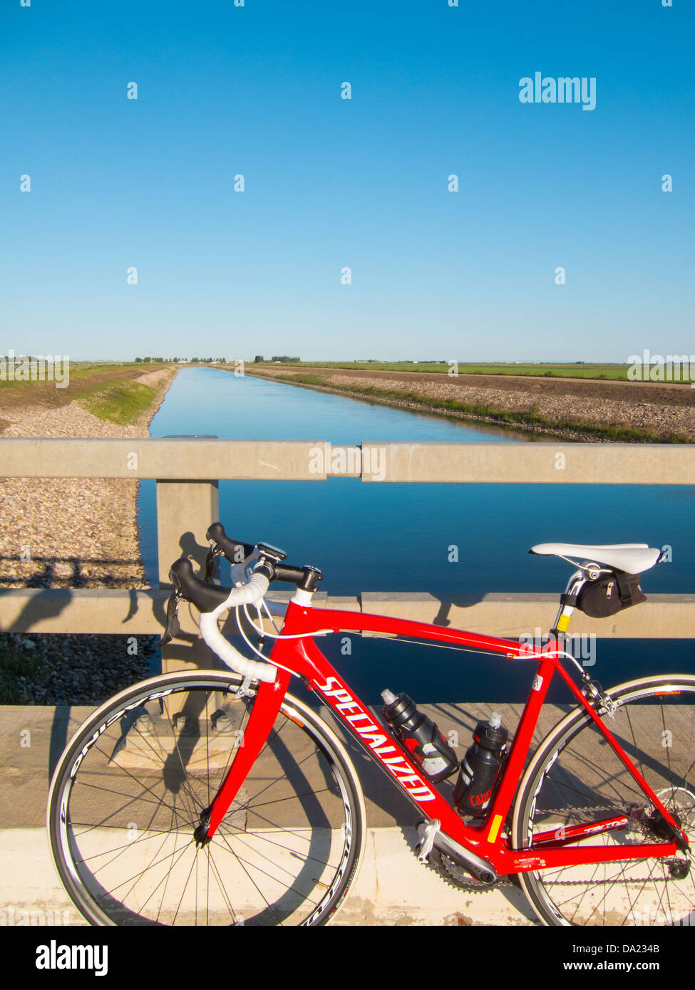 Red road bike by irrigation canal Stock Photo Alamy