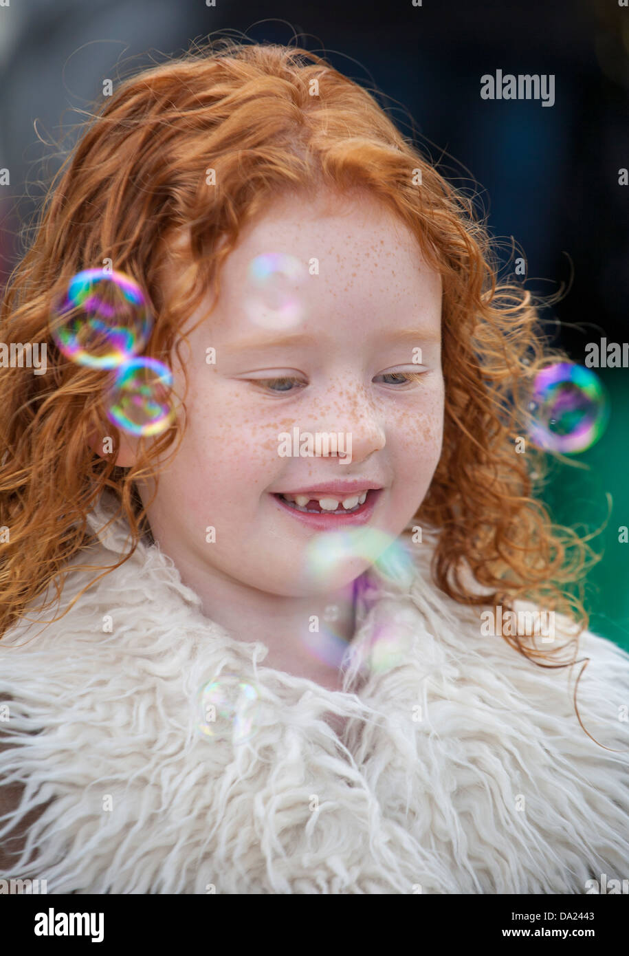 Young happy ginger haired girl playing with bubbles, Preston, UK Stock