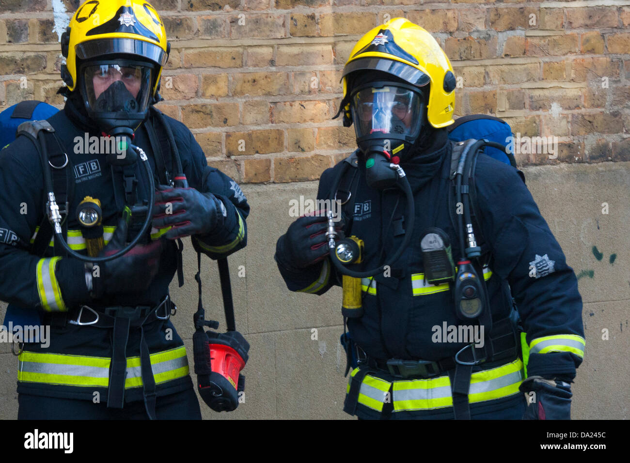 London, UK. 1st July, 2013. Firefighters wearing breathing apparatus  prepare to enter the still smouldering premises of The Wheel & Tyre Co in Kensal Green. Credit:  Paul Davey/Alamy Live News Stock Photo