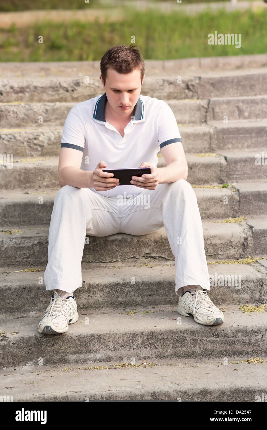 Young man sitting on a stairs with tablet pc outdoor Stock Photo - Alamy