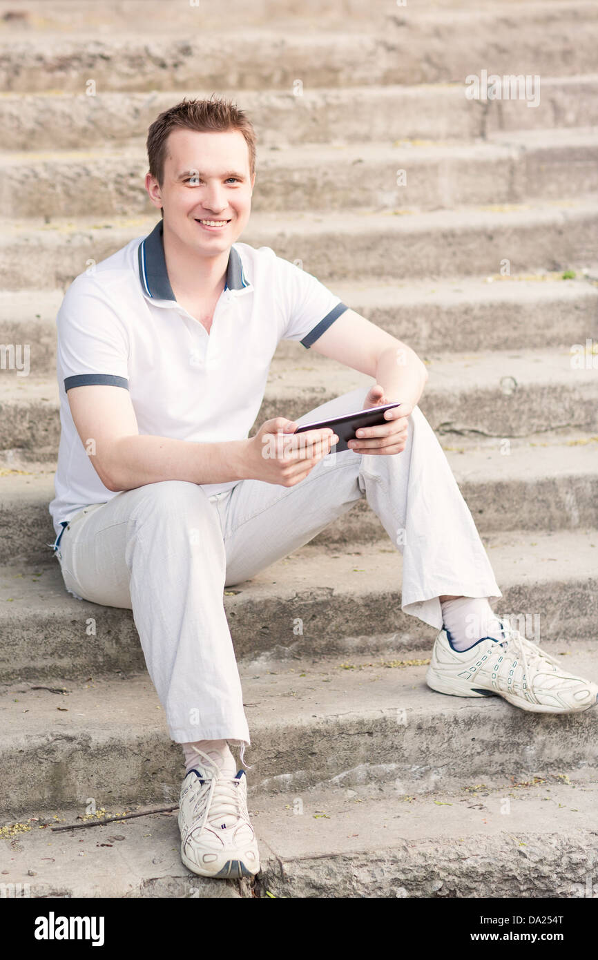 Young man sitting on a stairs with tablet pc outdoor Stock Photo - Alamy