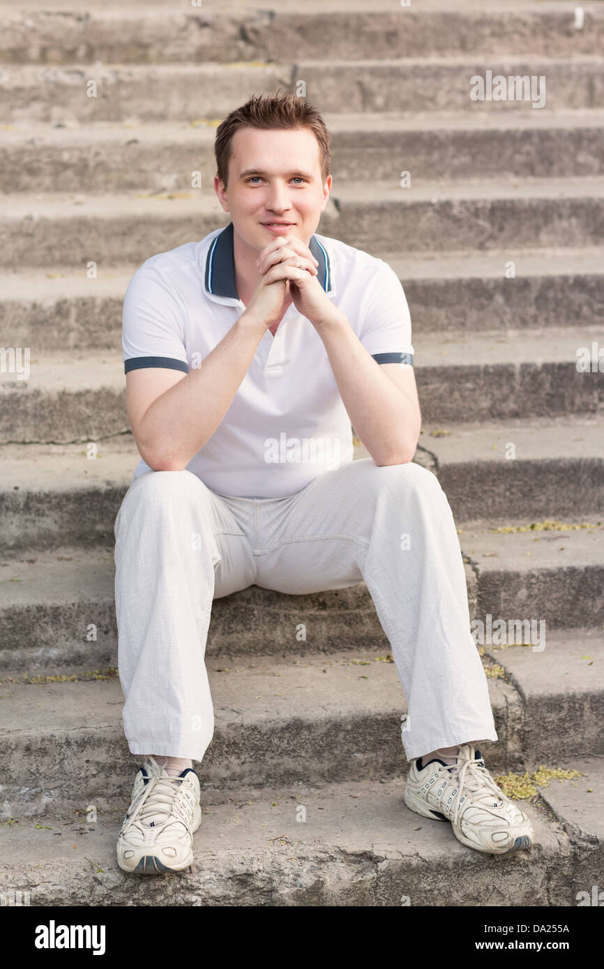 Young man sitting on stairs outdoor Stock Photo - Alamy