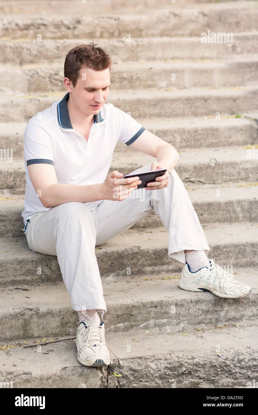 Young man sitting on a stairs with tablet pc outdoor Stock Photo - Alamy