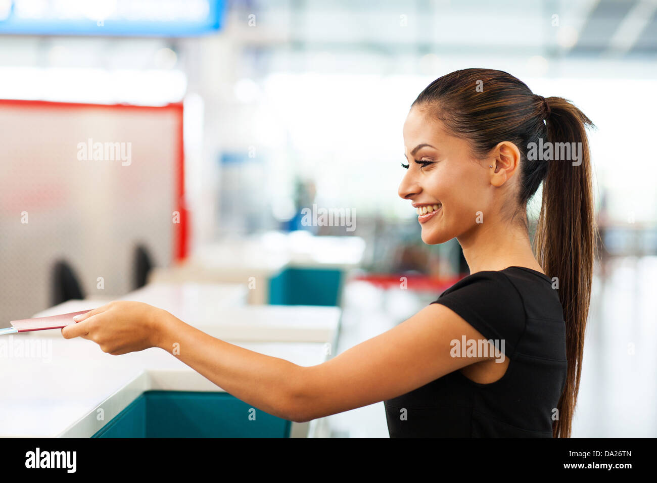 attractive businesswoman handing over air ticket at airport check in counter Stock Photo