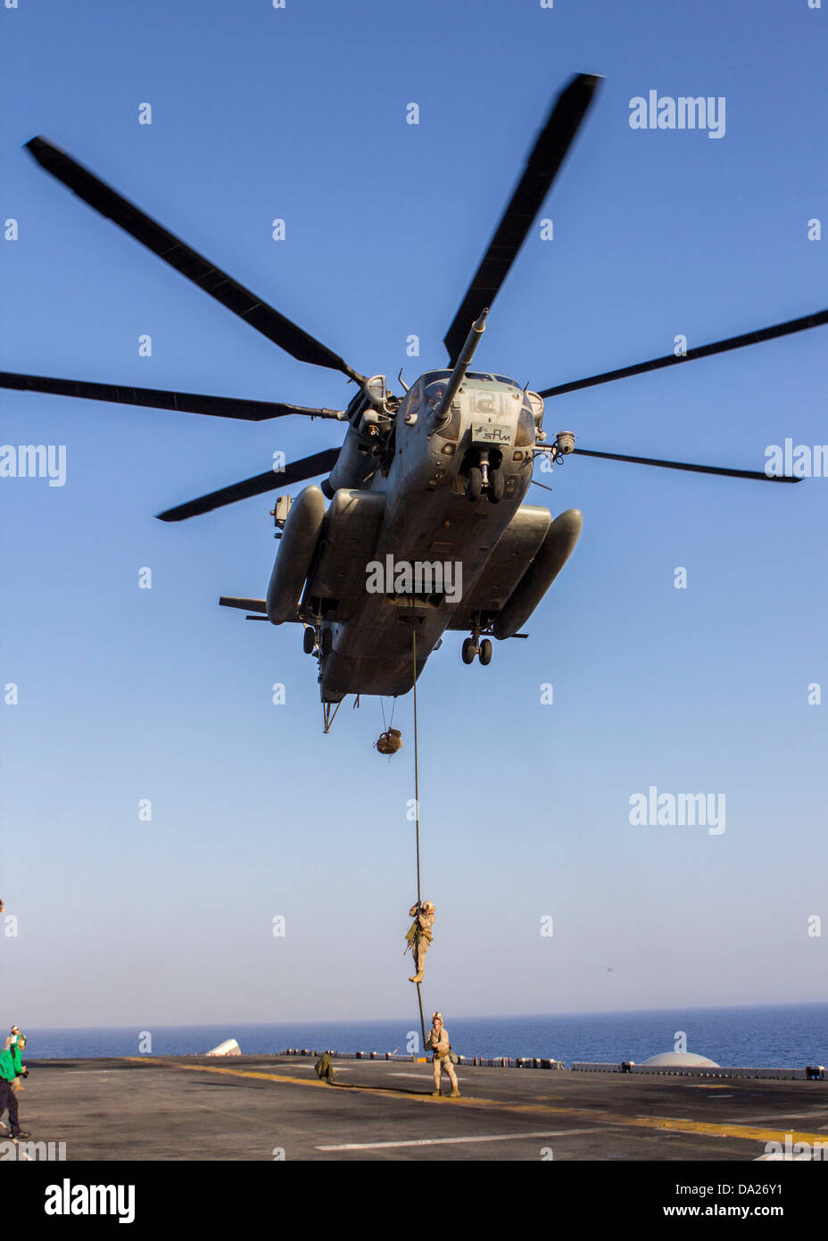 A US Marine assigned to Battalion Landing Team fast ropes from a CH-53 Super Stallion helicopter during familiarization training on the flight deck of the USS Kearsarge June 30, 2013. Stock Photo