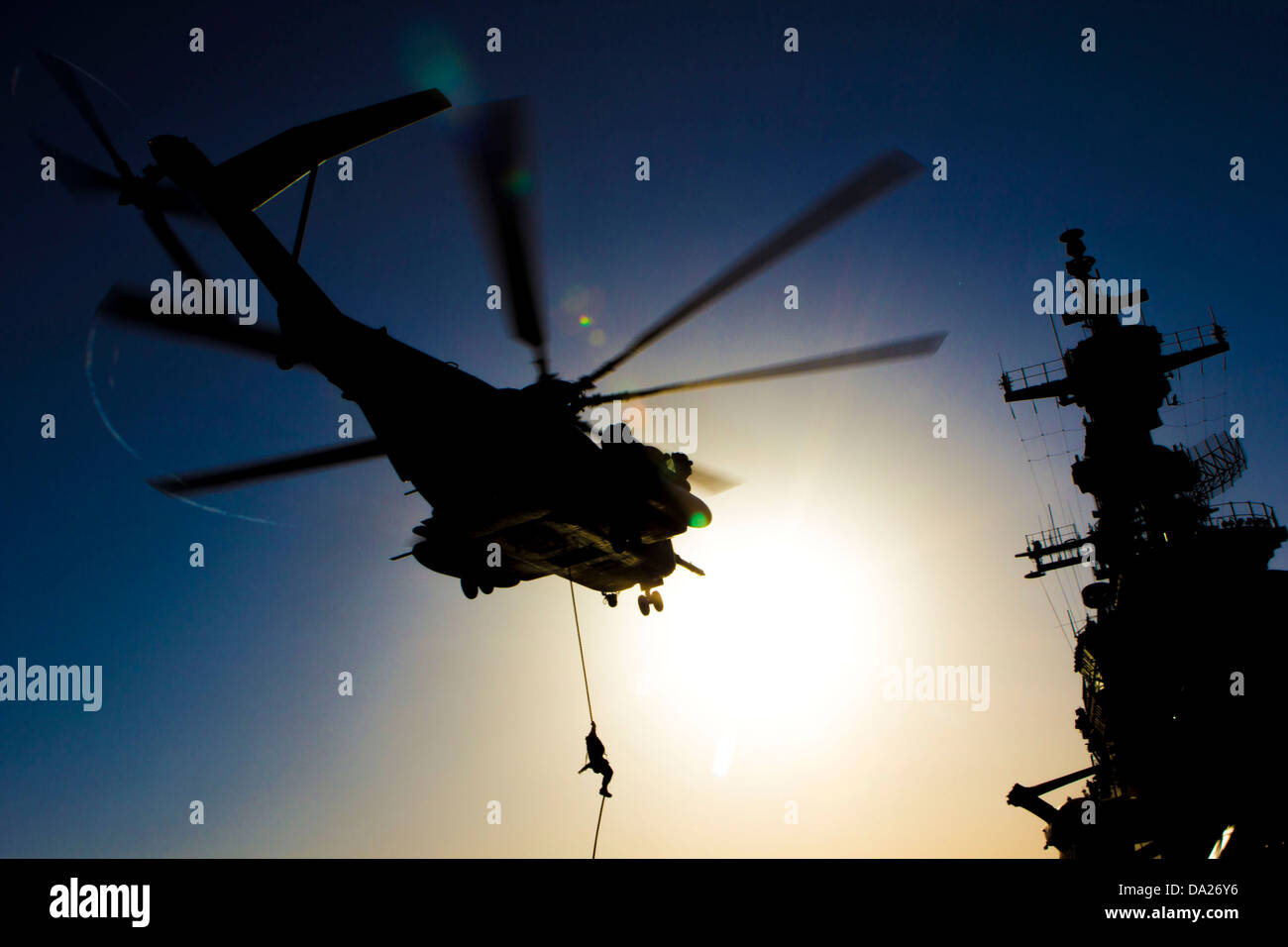 A US Marine assigned to Battalion Landing Team fast ropes from a CH-53 Super Stallion helicopter during familiarization training on the flight deck of the USS Kearsarge June 30, 2013. Stock Photo